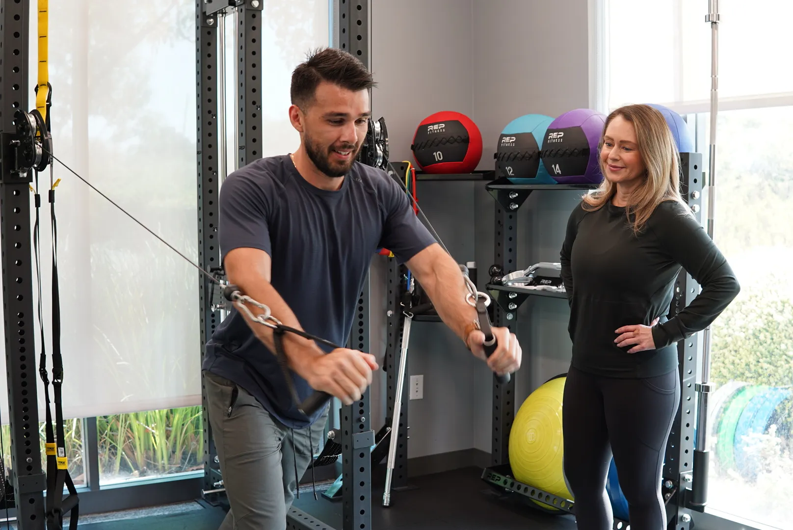Fit4Work trainer coaching an employee through a cable exercise in an office gym
